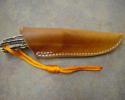 Custom leather knife sheath for a fixed blade, light tan in color with a notch for a thong.